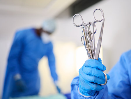 Hand, scissors and a doctor in a hospital or theatre to start operation with surgical tools. Zoom on a surgeon, assistant or staff with sterile equipment for medical procedure or emergency healthcareの写真素材