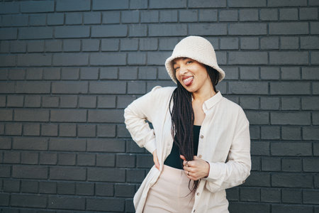 Fashion, happy and portrait of woman in city with trendy outfit, cool clothes and style for glamour. Beauty, smile and person on gray wall background with confidence, pride and cosmetics in townの写真素材