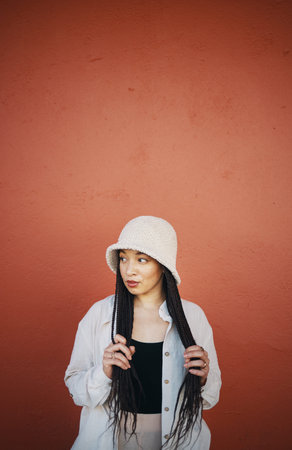Fashion, style and woman in city on orange wall background with trendy outfit, cool clothes and...