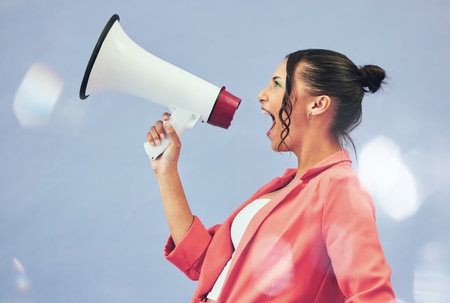 Megaphone, protest or motivation with a woman shouting on a blue background in studio for politics. Noise, change and a young speaker screaming into a bullhorn for leadership, justice or freedomの写真素材