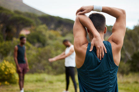 Stretching arm, fitness and exercise with a man outdoor for health and wellness. Behind runner, athlete or sports person in nature park to start morning run, workout or training with muscle warm upの写真素材