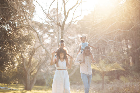 Parents with children in woods, piggy back and walking for love, bonding or peace in nature together. Mother, father and kids on shoulders in garden, black family on summer weekend in park or forrestの写真素材