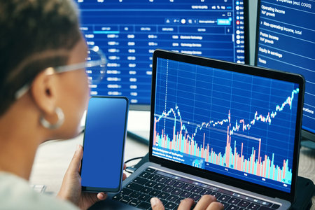 Person, phone and laptop on stock market in fintech, trading or online business finance at office....