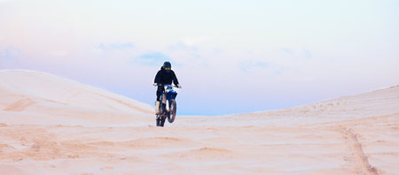 Rally, desert or athlete driving motorcycle for action, adventure or fitness with performance or adrenaline. Sand, sports or person on motorbike on dunes for training, exercise or race or challengeの写真素材