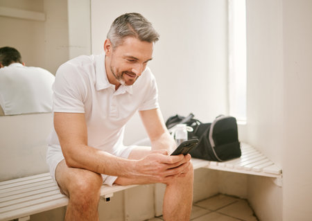 Tennis, phone and man typing on social media after exercise, workout or training in a sports club change room. Smile, connection and athlete chatting on mobile app for communication online or webの写真素材