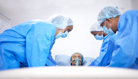Patient, hospital and surgeon team with bed for emergency, healthcare or medical procedure. Doctors with a man to start collaboration, healing or surgery and operation with support and scrubs in ICUの写真素材