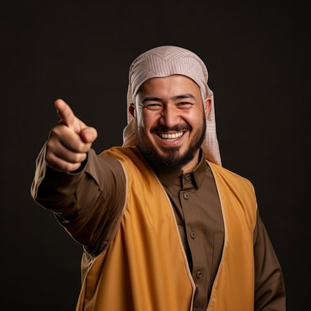 Happy muslim man, smiling and pointing on clear backdrop. Religion concept.の素材