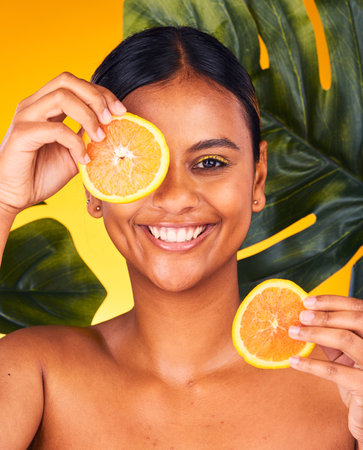Woman, orange and beauty with natural skincare, dermatology and cosmetics portrait on yellow background. Monstera, citrus fruit and vegan treatment, green facial for vitamin c and skin glow in studioの写真素材