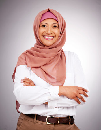 Portrait, beauty and smile with a muslim woman arms crossed in studio on a gray background. Islam,...