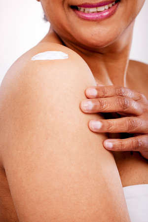 Skincare, studio shoulder or person with cream, ointment or SPF sunscreen lotion for skin hydration, protection or treatment. Body moisturizer, cosmetics product or closeup model on white backgroundの写真素材