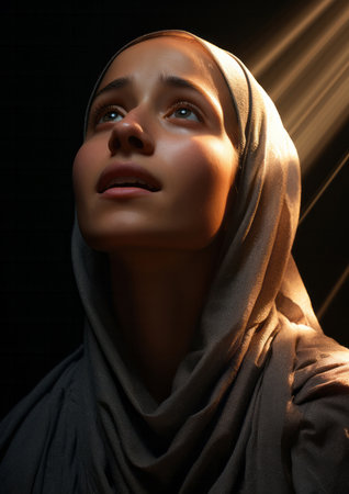 Young muslim woman lifting her head in prayer. Sunlight on her face. Religion concept.の素材