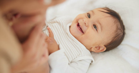 Baby child, mother and peekaboo on bed with stretching legs, game and funny surprise in family...