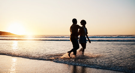 Beach sunset, sea water and silhouette couple walking, connect or enjoy romantic holiday in South Africa. Love, ocean waves and dark shadow of summer people bond, talking and relax on evening journeyの写真素材