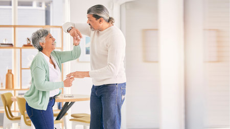 Mature couple, dancing and happy at home for anniversary, birthday or valentines celebration. Laugh, love and care of a man and woman for healthy marriage, happiness and romance with mockup spaceの写真素材