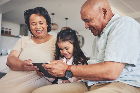 Happy family, child or grandparents with tablet for elearning or studying for education or remote learning at home. Development, grandfather or grandma with girl reading online ebook or playing gamesの写真素材