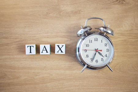 Taxes, clock and finance with building blocks on table from above for planning, future and...