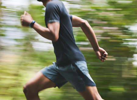 Man, motion blur and running in park for exercise, fitness action and power of cardio workout. Closeup, runner and sports athlete training for marathon with energy, speed and fast performance outdoorの写真素材