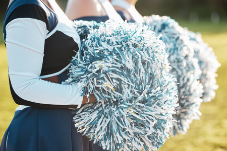Cheerleader team, sports and hands with pompom for dance, performance and motivation for game. Teamwork, dancer and people in costume cheering for support in match, competition and event outdoorsの写真素材