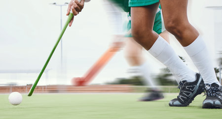 Person, feet and hockey stick on field, ball with speed or motion for sports goal, training or professional game. Action, legs and turf with performance for outdoor competition, fitness and exerciseの写真素材
