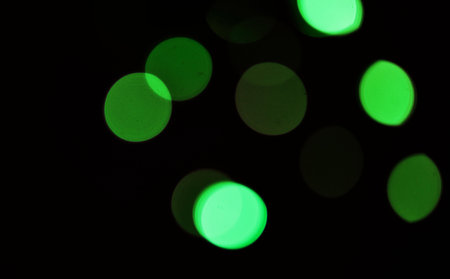 Green, bokeh and light in a studio with a dark background for celebration, event or party. Mockup, sparkle and color for glow, magic or shine for festive decoration by a black backdrop with mock up.の写真素材