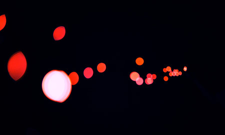 Bokeh, cosmic red dots and black background with pattern, texture and mockup with aesthetic lights. Night lighting, sparkle particles and glow on dark wallpaper with space, color shine and flare.の写真素材