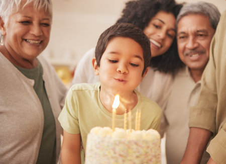 Birthday party, happy family and child with cake blowing candle in a home for event to celebrate together in a house. Grandparents, happiness and kid excited for gathering, surprise and giftの写真素材