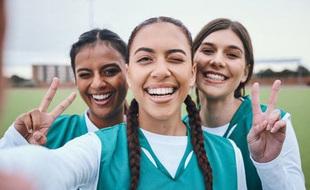 Sports selfie, girl team and peace sign on field for memory, competition and portrait for fitness. Women group, photography and wink on social network with emoji, v icon and diversity for hockey gameの写真素材