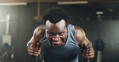 Black man at gym, weight sled and muscle endurance, strong body and core balance power in fitness. Commitment, motivation and bodybuilder in workout challenge for health and wellness on push machine.の写真素材