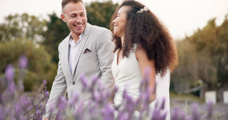 Wedding, walking and field with couple, marriage and funny with love, commitment and happiness. Happy people, bride and groom outdoor, romance and countryside with trust, bonding and conversationの写真素材