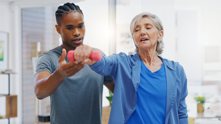 Senior woman, nurse and rehabilitation with dumbbells exercise in a nursing home for fitness....