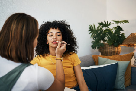 Makeup artist, girl friends and lips with cosmetics and lipstick of women in a living room on a sofa. Couch, skincare and brush in a lounge at home with lip tutorial and beauty for client cosmetologyの写真素材