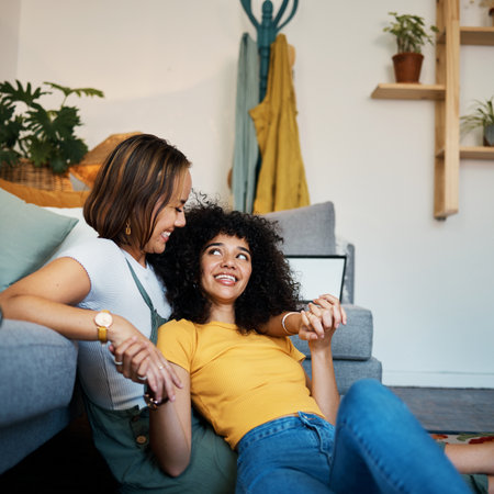 Lesbian, couple and relax on couch in communication at home for support, trust and partnership. Happy lgbt woman, living room or smile for identity or equality love in house, commitment or togetherの写真素材