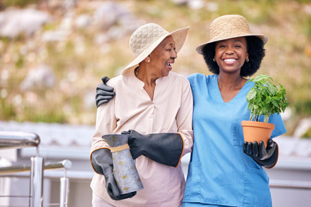 Old woman, gardening and portrait with nurse outdoor with plant, flowers and happiness in backyard nature. Happy, senior and african caretaker with wellness or agriculture greenery in retirementの写真素材