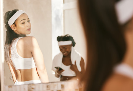 Women, mirror and gym in sportswear, body image issue and thinking of health, wellness and fitness. Sports club, workout partner and exercising for tennis competition, comparison and insecure thoughtの写真素材