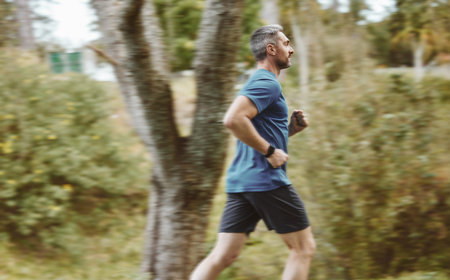 Man, running and forest in workout, training or outdoor cardio exercise for healthy wellness or weight loss. Active male person, athlete or runner in sports run, sprint or race for fitness in natureの写真素材