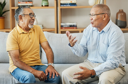 Senior, men and communication on sofa for support, relax and retirement in living room of home with smile. Elderly, people or conversation on couch for advice, discussion and care in lounge of houseの写真素材