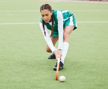 Hockey, sports or girl on turf in fitness training, game or competition with ball, stick or action. Strong woman, athlete or female player in exercise, workout or motion on artificial grass for powerの写真素材