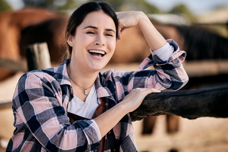 Smile, equestrian and horse riding with a woman jockey on a farm or ranch for training and practice. Cowboy, western and a happy young rider outdoor in the countryside for recreation or leisure hobbyの写真素材