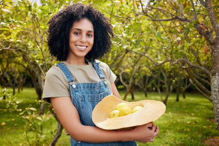 Woman in orchard, nature and agriculture with lemon in portrait, healthy food and nutrition with citrus farm outdoor. Farmer, picking fruit and smile with harvest, sustainability and organic productの写真素材