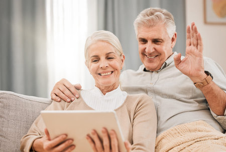 home, video call and senior couple with a tablet, greeting and wave with connection, smile and retirement. Technology, old man or elderly woman on a couch, social media and online chatting with helloの写真素材