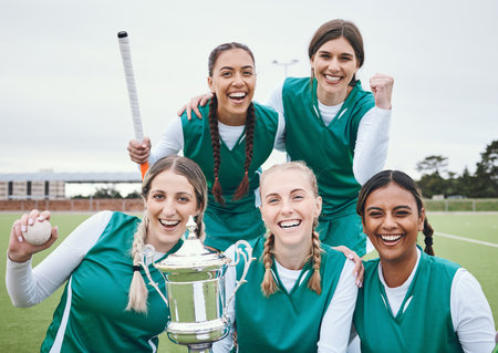 Women, hockey team and winning trophy in portrait, celebration and success in competition on field. Champion girl group, friends and diversity for sports, goal or happy outdoor at stadium for contestの写真素材