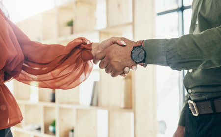 Creative people, handshake and partnership in meeting, b2b deal or teamwork together at office. Closeup of man and woman shaking hands for startup, introduction or thank you in agreement at workplaceの写真素材