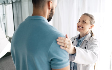 Doctor, patient and woman touch shoulder for support in consultation for healthcare, wellness or empathy. Happy medical professional comfort man for care, kindness and mature surgeon help in hospitalの写真素材