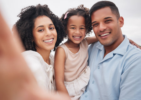 Selfie, portrait and a family at the beach for memory, bonding or fun on a vacation. Happy, travel and a mother, father and girl kid taking a photo at the ocean for summer freedom, love and careの写真素材