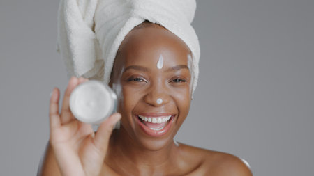 Black woman, face and beauty with skincare, lotion for facial with natural cosmetics on grey background. Portrait, dermatology and African model with cream, moisturizer and treatment in studioの写真素材