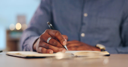 Businessman, writing and book for schedule planning, ideas or brainstorming strategy on table at office. Closeup of male person, hands or employee taking notes for project plan or agenda at workplaceの写真素材