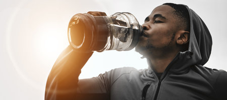 Black man, fitness and drinking water on break for hydration, workout or exercise in motivation. Banner of African male person with sports or mineral drink for natural sustainability or recoveryの写真素材