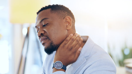 Black man, neck pain and injury at office in stress, pressure or burnout from mistake or anxiety. Tired African businessman, person or employee with sore ache, strain or overworked at workplaceの写真素材