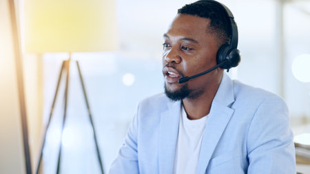 Call center, crm and black man talking for telemarketing, tech support or contact us at help desk in office. Customer service, sales agent and serious consultant in communication, advice and businessの写真素材