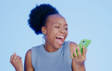 Celebration. phone and young black woman in a studio with winning, achievement or success. Happy,...